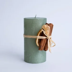 Lumânare decorativă verde cu portocală uscată și scorțișoară din material nedefinit, decor elegant și cadou ideal pentru sărbători.