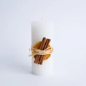 Lumânare decorativă albă cu portocală uscată și scorțișoară din material nedefinit, decor elegant și cadou ideal pentru sărbători.