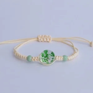 Brățară mărțișor cu floare verde în rășină și șnur împletit crem din rășină, floare naturală uscată, șnur textil împletit, mărgele acrilice, decor elegant și cadou ideal pentru sărbători.